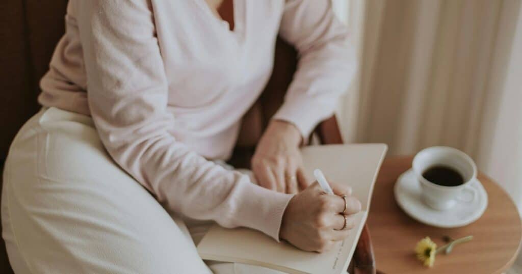 Midlife woman in soft light looking thoughtful, and writing in a journal representing ADHD symptoms becoming harder to manage during perimenopause and menopause