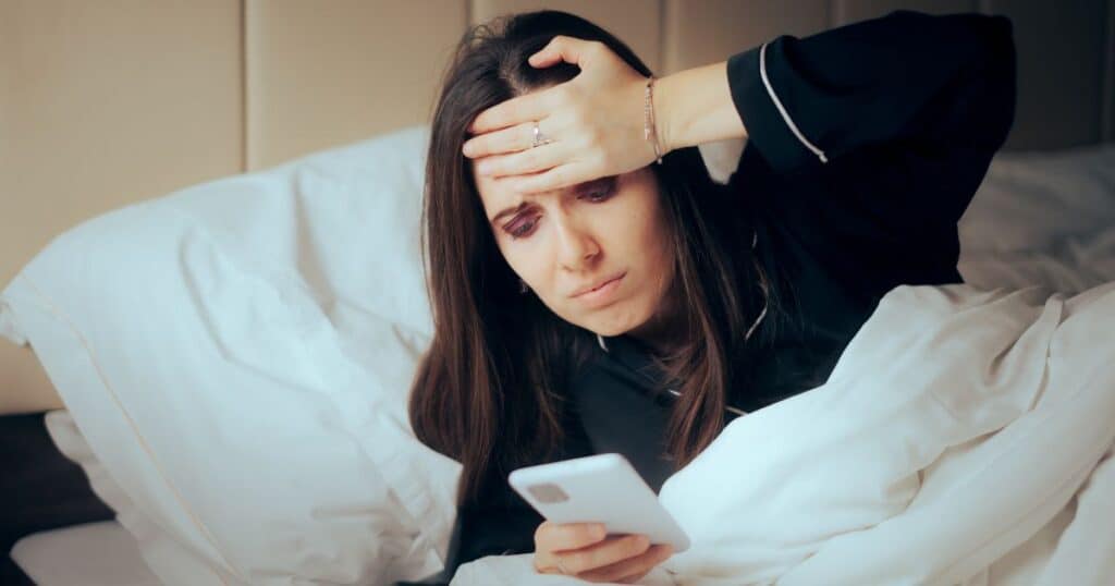 Woman looking at her phone with a worried expression, representing rejection sensitive dysphoria in ADHD